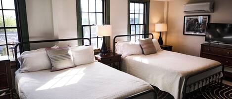 A hotel room with two beds, a television, and a window with a view.