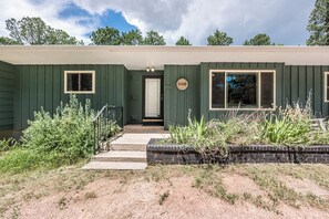 Una casa verde a un piano con una porta d'ingresso, due finestre e una cassetta delle lettere.