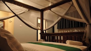 Ein Schlafzimmer mit einem Himmelbett, einer grünen Tagesdecke und einem Holz-Kopfteil.