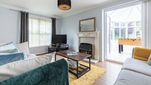 Ein Wohnzimmer mit einer Couch, einem Couchtisch, einem Kamin und einem Fernseher.