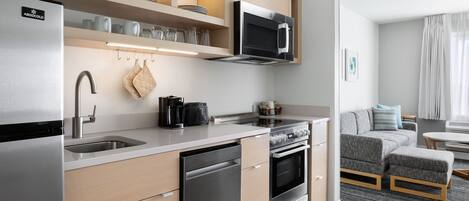 A modern kitchen with stainless steel appliances, wooden cabinets, and a built-in oven.