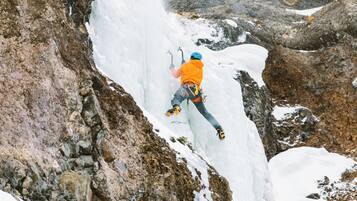 A person ice climbing on a steep, rocky mountain.