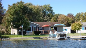 A houseboat docked at a marina with a covered deck and a small boat in the foreground. - Eagle's View Indiana waterfront home on a premier fishing lake pontoon included! (Silver Lake)