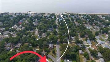 Luchtbeeld van een woongebied met huizen, wegen en een strand op de achtergrond.