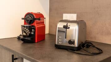 A red coffee maker and a silver toaster on a kitchen counter.