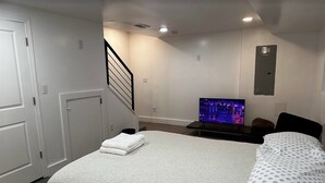 A bedroom with a bed, a TV, a staircase, and a door. - Quaint 3/2.5 home in Fort Dupont (Washington)
