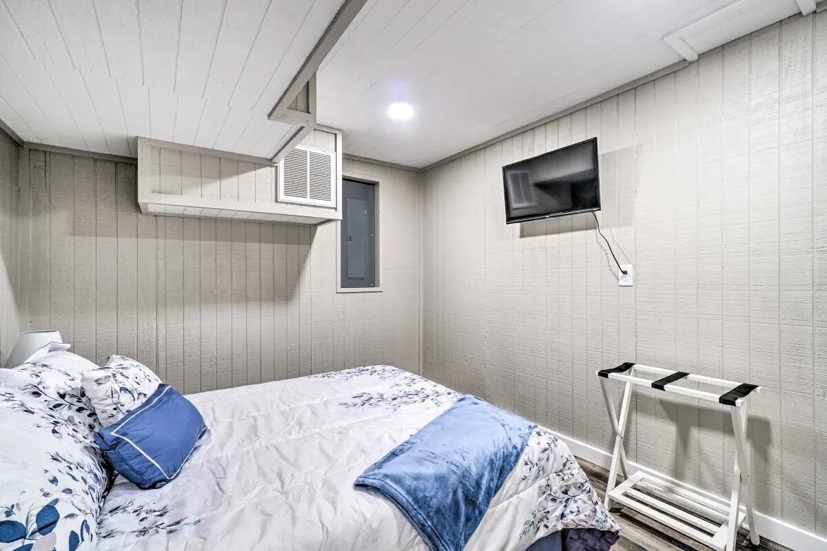 A bedroom with a bed, a mounted TV, a window, and a white radiator.