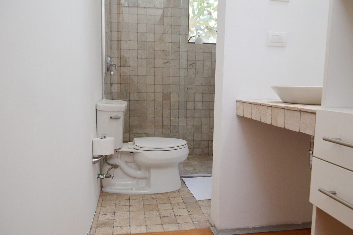 A small, clean bathroom with a toilet, a sink, and a tiled shower area.