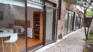 Un dormitorio moderno con puerta de vidrio, cama, mesita de noche y una silla.