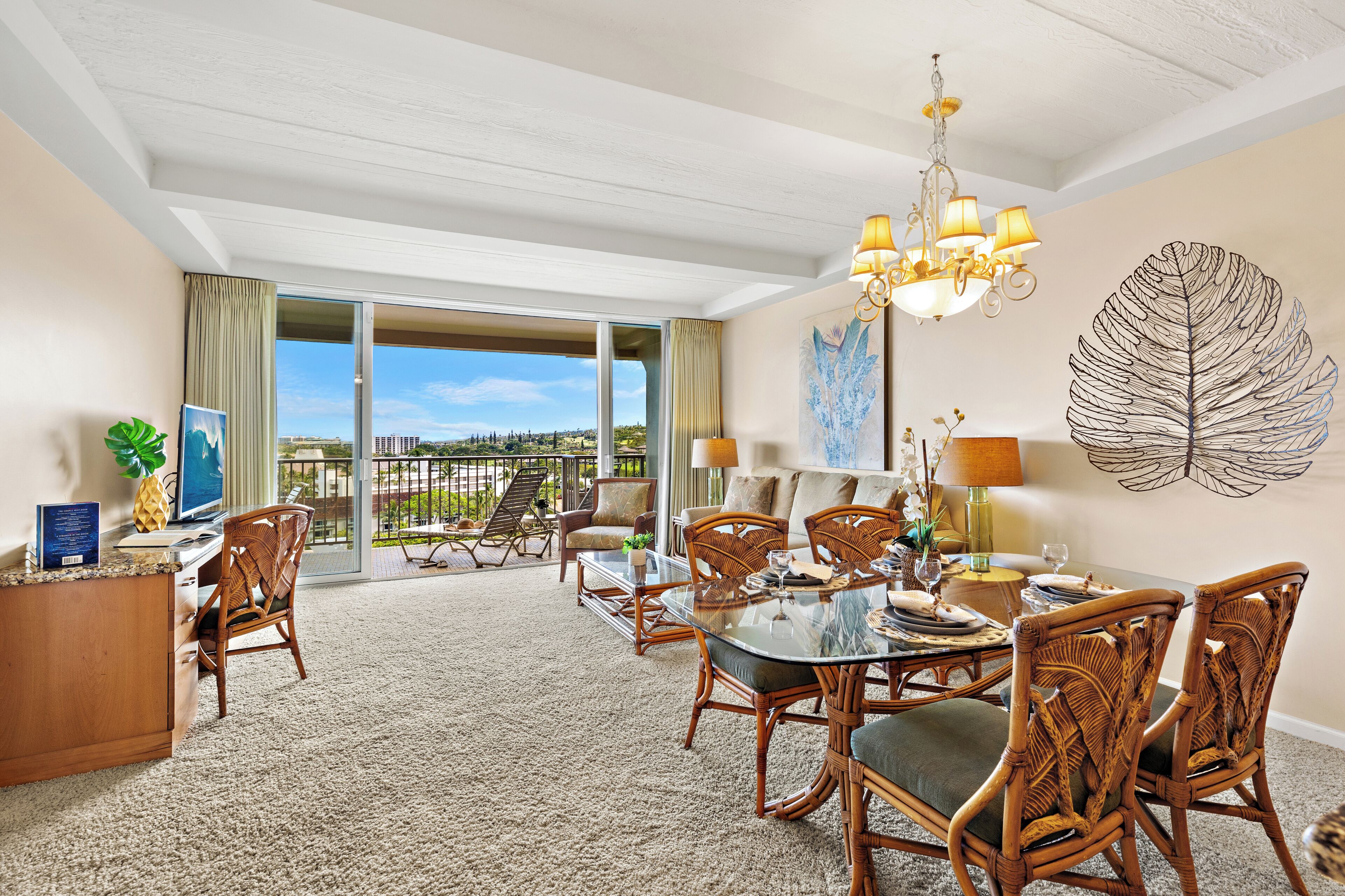 A hotel room with a dining area, a desk, and a large window with a view of the outdoors.
