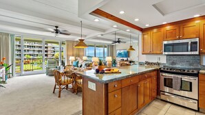 A spacious kitchen with wooden cabinets, a large island, and a built-in microwave. - Ocean View steps from beach, dining, shopping 260 (Lahaina)