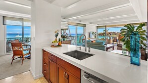Een moderne keuken met een groot kookeiland, een eethoek en uitzicht op de oceaan.