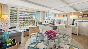 A modern hotel room with a balcony, a bed, a dining area, and a view of the cityscape. - Ocean View steps from beach, dining, shopping 462 (Lahaina)