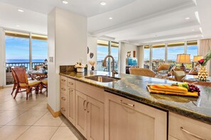Enjoy ocean views from this spacious kitchen with a large island, stainless steel sink, and granite countertop, perfect for cooking and dining.