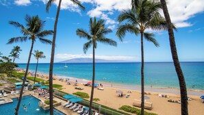 A beach resort with a swimming pool, palm trees, and a view of the ocean. - Ocean View steps from beach, dining, shopping 970 (Lahaina)