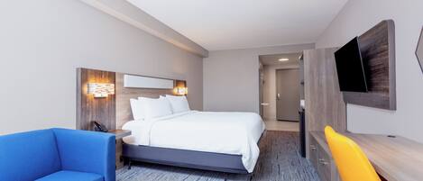 Una habitación de hotel moderna con una cama grande, un sofá azul, un escritorio de madera y una silla amarilla.
