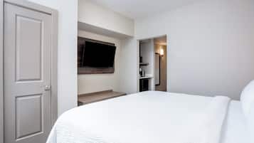 A hotel room with a bed, a television mounted on the wall, and a bathroom visible through an open door.