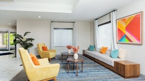 Una sala de estar moderna con un sofá, sillones, una mesa de centro y un amplio ventanal con cortinas.
