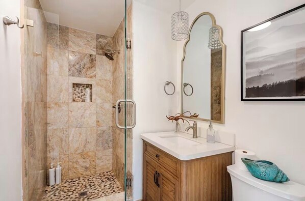Een moderne badkamer met douche, wastafel en een grote spiegel.
