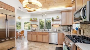 Een moderne keuken met roestvrijstalen apparatuur, houten kastjes en een groot raam dat voor natuurlijk licht zorgt.