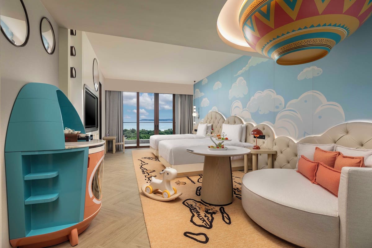 A modern hotel room with a large bed, a sofa, a TV, and a unique ceiling design.