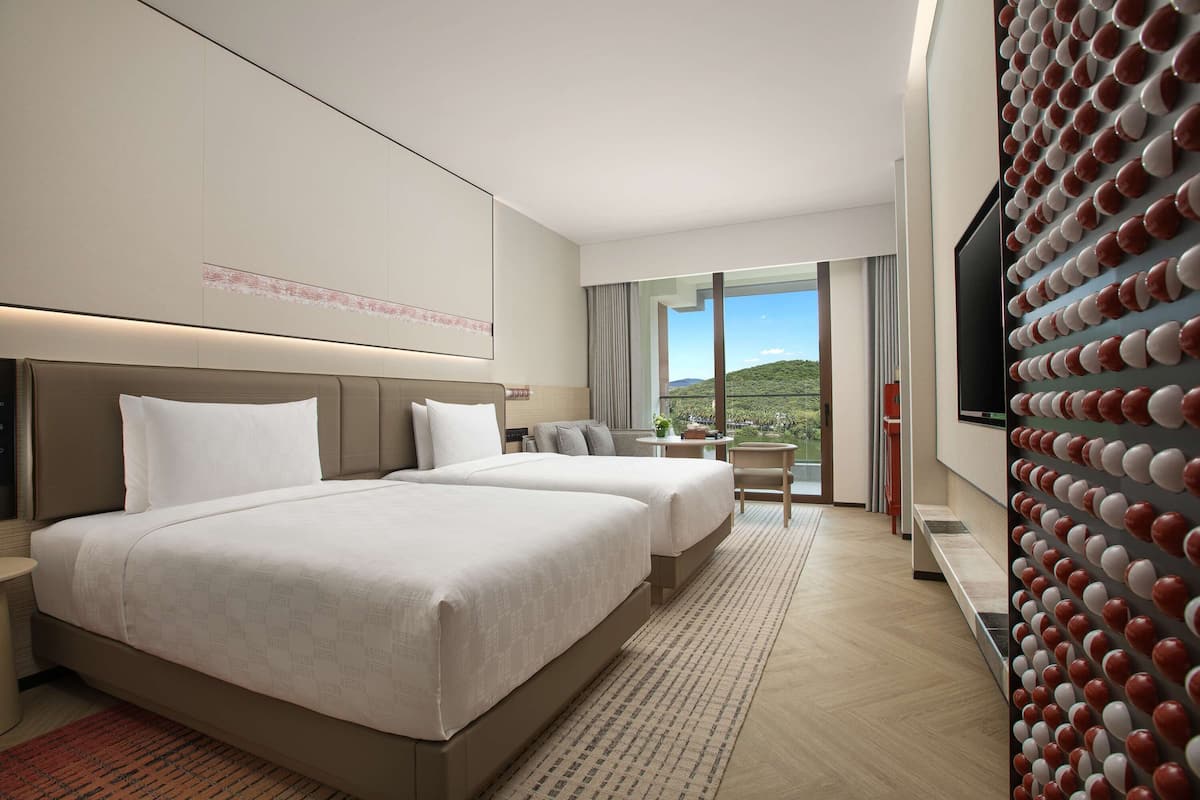 A hotel room with two beds, a dining area, and a large TV wall.