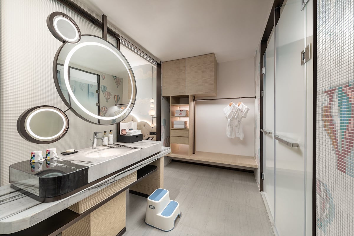 A modern bathroom with a large mirror, two smaller mirrors, a vanity with a sink, and a shower area.