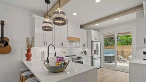 A modern kitchen with white cabinets, a central island, and a dining area with wicker chairs.