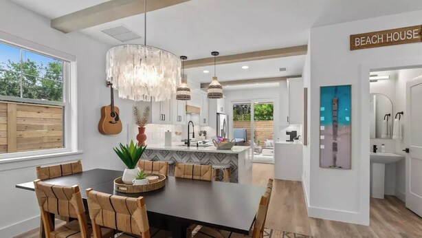 A modern kitchen with white cabinets, a central island, and a hanging light fixture.
