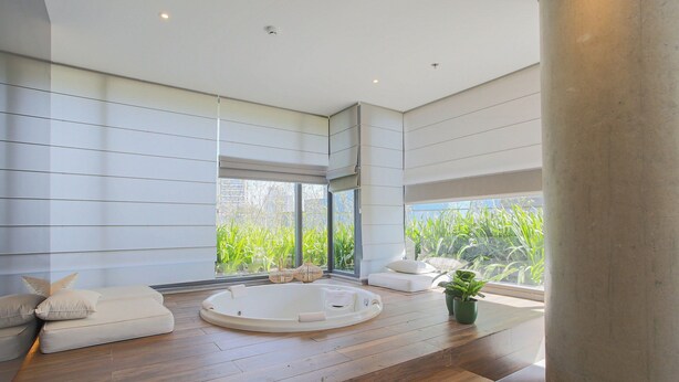 A modern bathroom with a wooden floor, a bathtub, and a window with a view of greenery. - Parque Jockey Pinheiros (São Paulo)