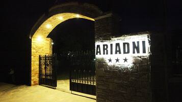 A stone archway leading to a gated entrance with a sign that reads "ARIADNI".