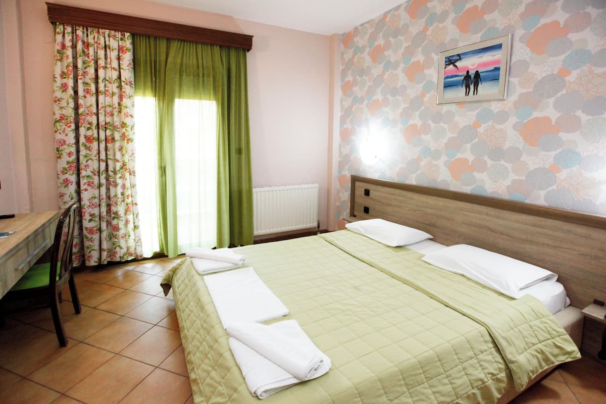 Un dormitorio con cama, escritorio y ventana con cortinas.