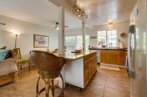Relax in this spacious living area with a central kitchen island, comfortable seating, and a high ceiling with exposed beams.