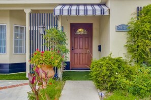 Welcome to a charming home with a beautifully maintained front yard, featuring a variety of plants and a potted flower arrangement.