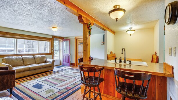 A cozy living room with a sofa, a patterned rug, and wooden chairs. - Secluded Stonewall Cabin w/ Mountain View! (Weston)