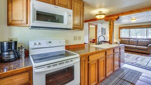 A kitchen with wooden cabinets, a microwave, a stove, and a coffee maker. - Secluded Stonewall Cabin w/ Mountain View! (Weston)