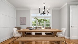A dining area with a wooden table and benches, a chandelier, and a window with greenery. - Woodland View (Smithfield)