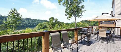Une terrasse dotée de mobilier d’extérieur, d’un barbecue et offrant une vue sur une zone boisée.