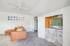 Un interior modern amb un sofà, un ventilador de sostre, una zona de cuina i un passadís.