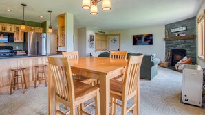 A modern kitchen with wooden cabinets, a stainless steel refrigerator, and pendant lighting.