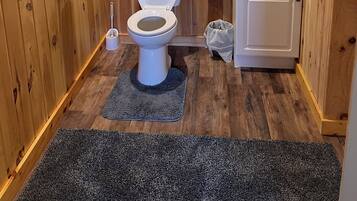 Un baño pequeño con inodoro, lavabo y estantes para almacenamiento.