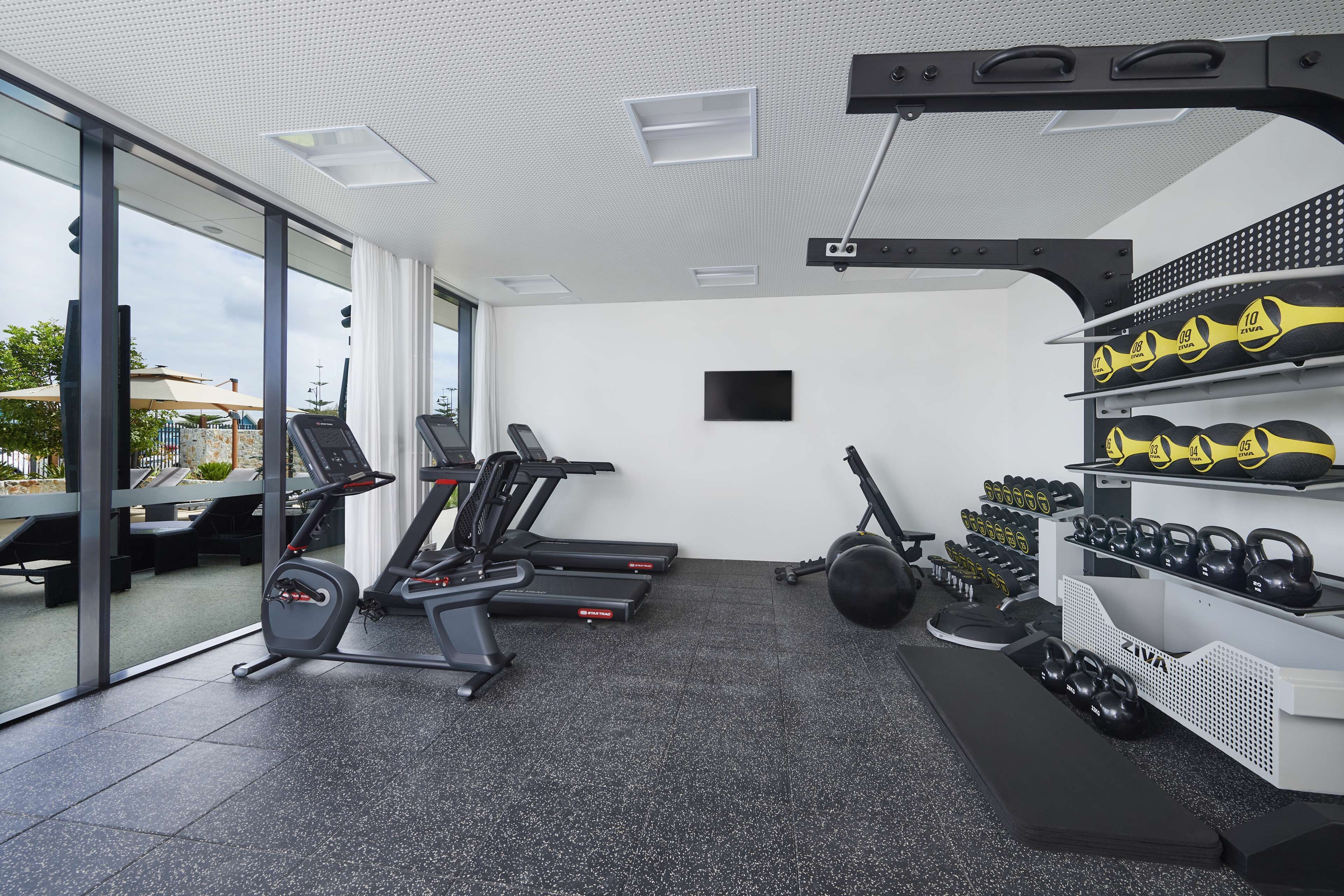 A gym with treadmills, weight machines, and kettlebells.