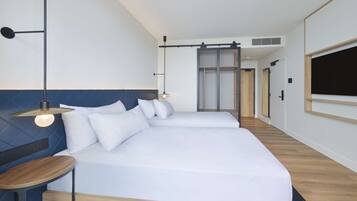 Une chambre d’hôtel moderne avec un grand lit, des tables de chevet et un téléviseur fixé au mur.