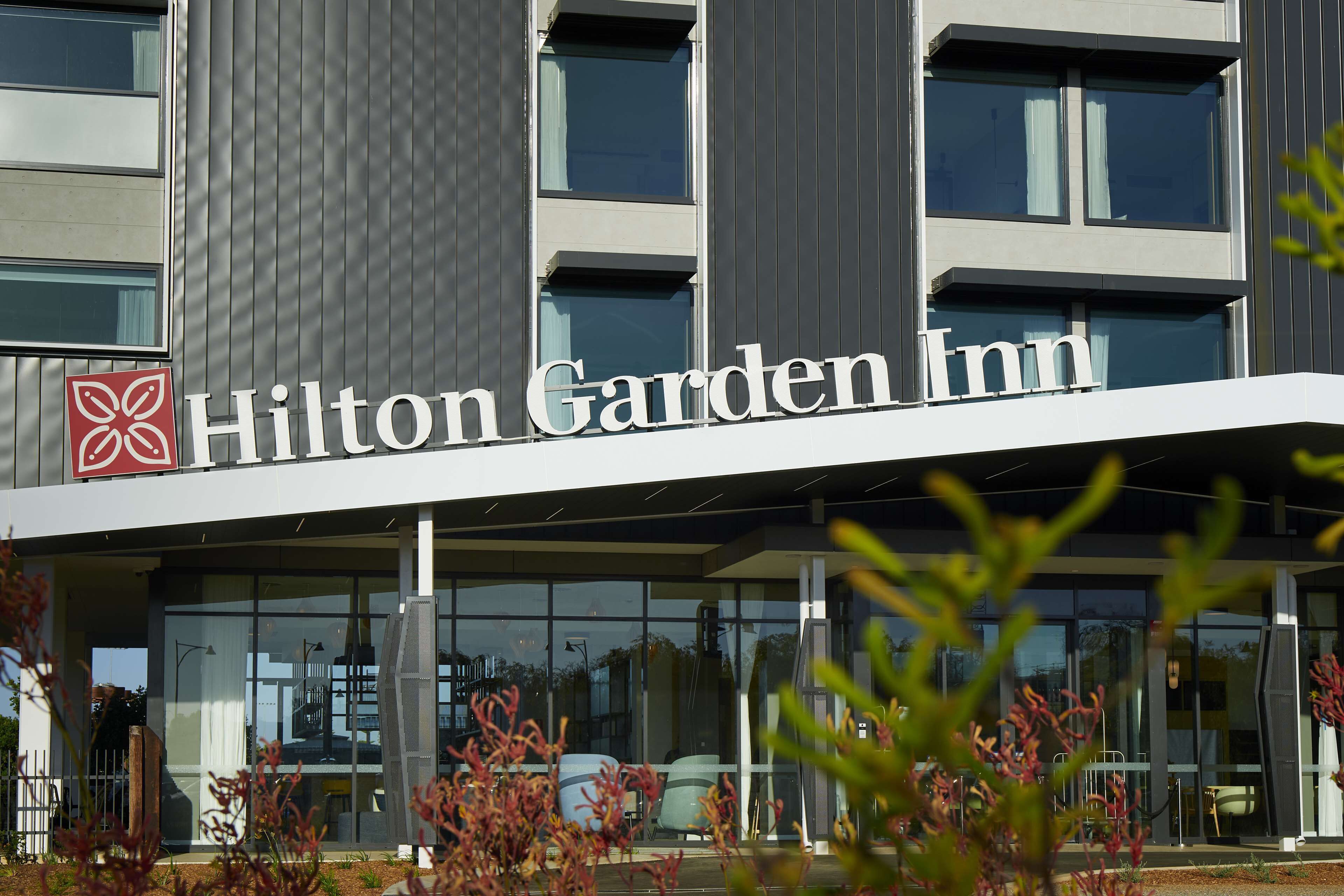 The exterior of a Hilton Garden Inn with a modern design, large windows, and a prominent signage.