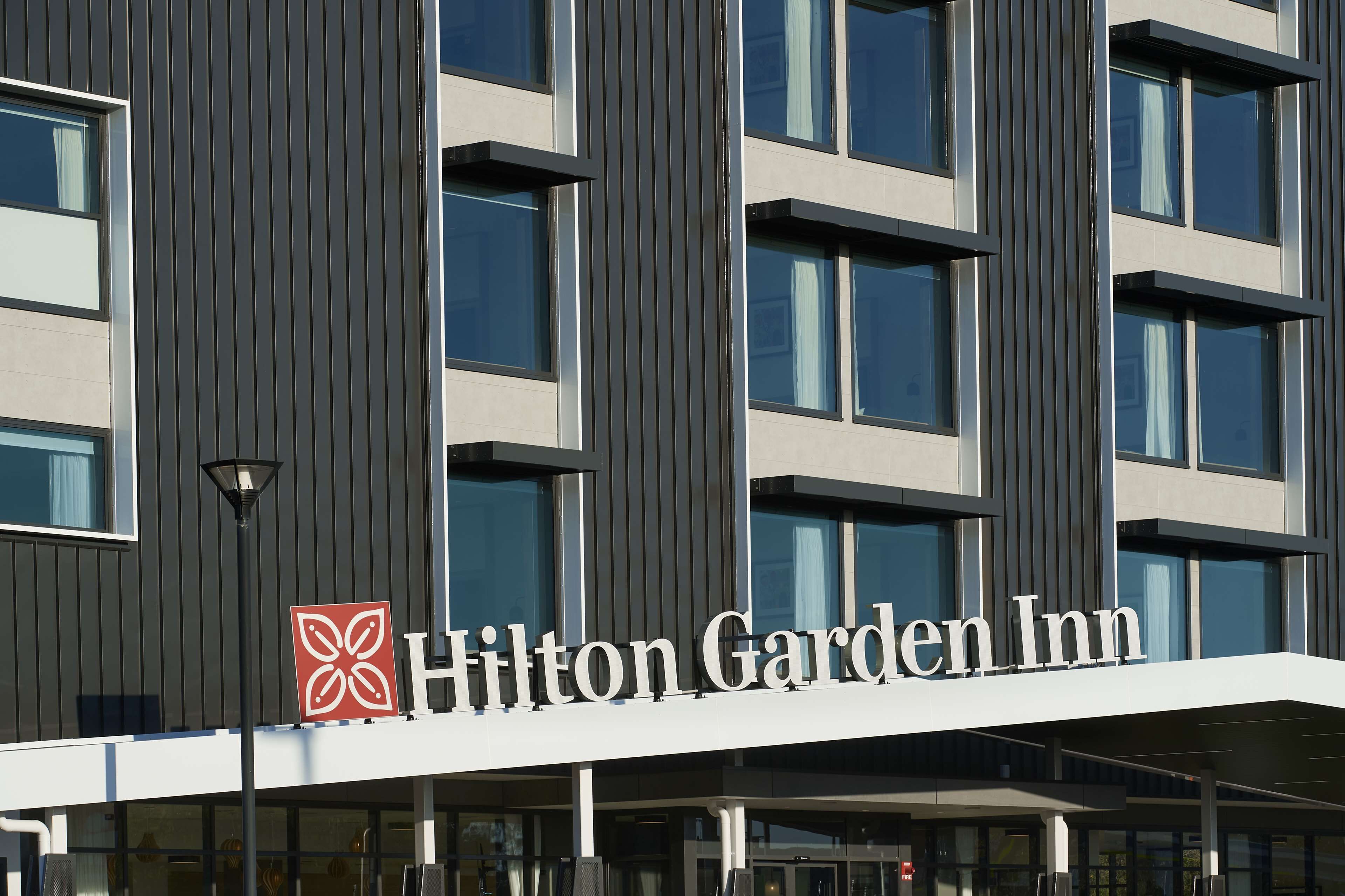 A Hilton Garden Inn building with a modern facade, large windows, and a prominent logo.