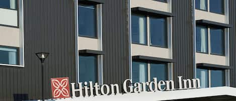 Un edificio de Hilton Garden Inn con fachada moderna, ventanas amplias y un logotipo destacado.