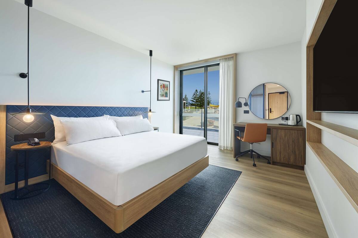 Habitación de hotel moderna con cama, escritorio y vistas al exterior.