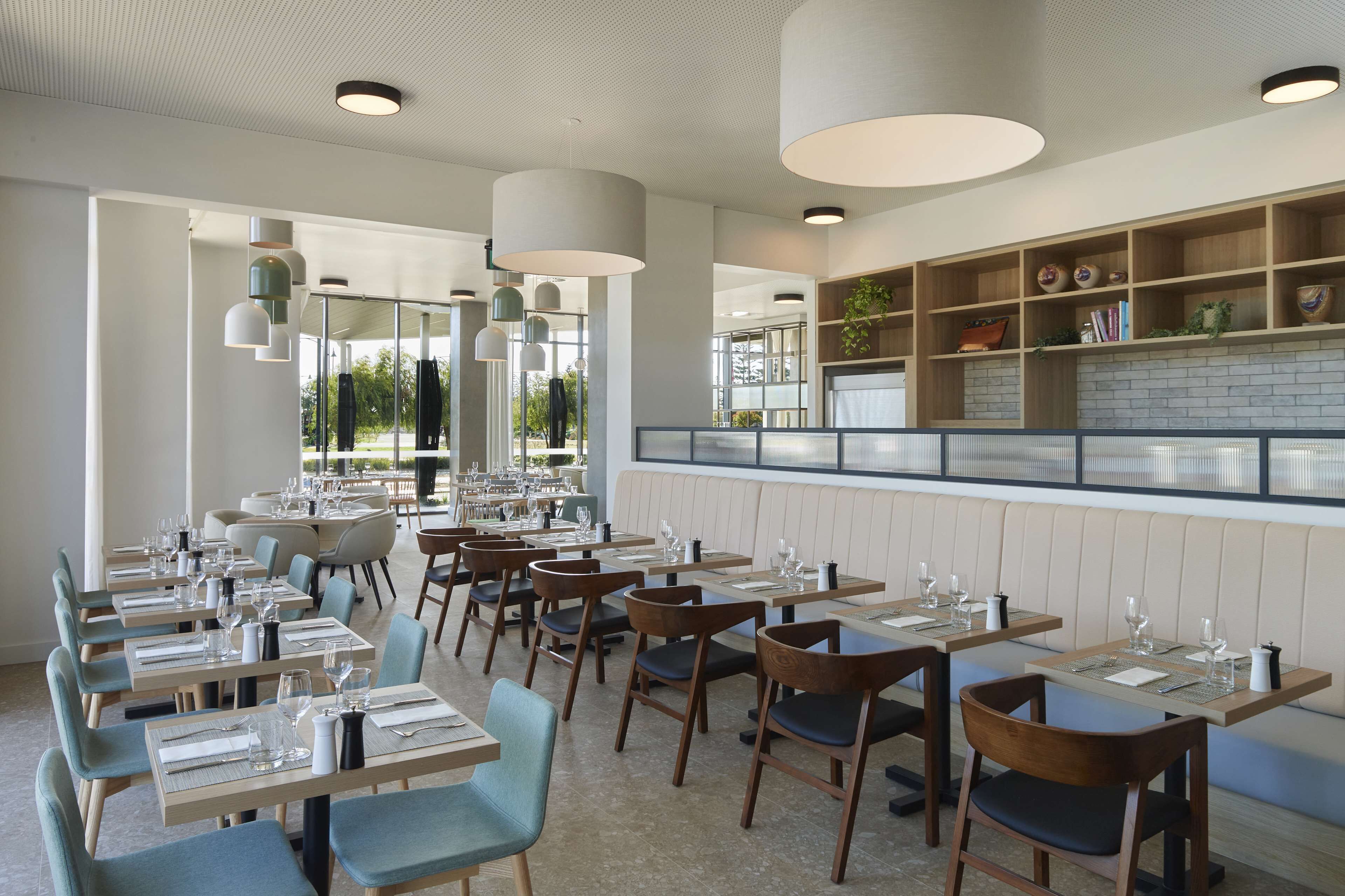 Un restaurante con varias mesas y sillas, una zona de bar y vistas al exterior.