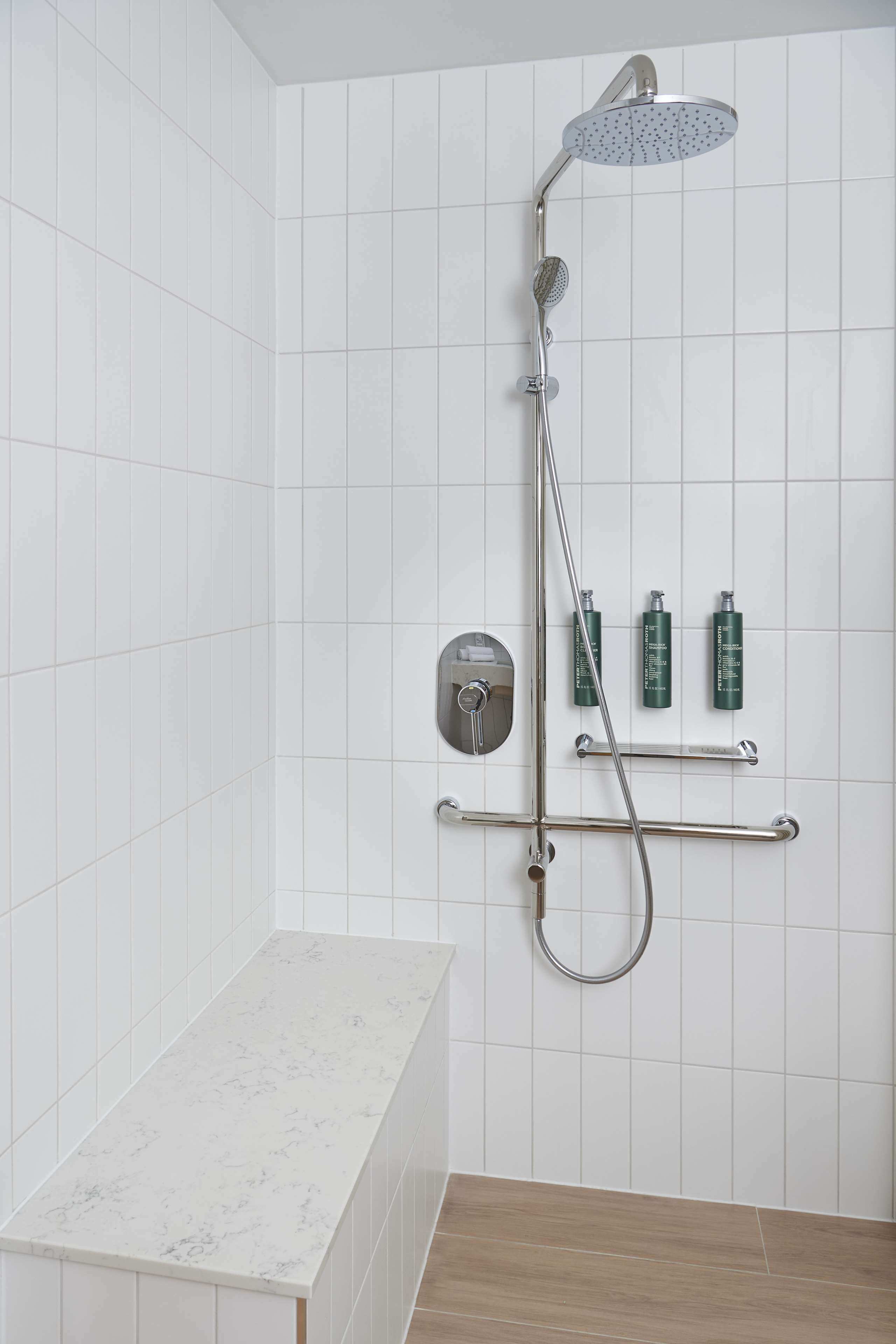 Une salle de bain avec une douche, un comptoir en marbre et un plancher en bois.