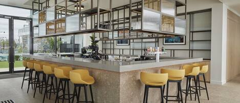 A modern kitchen with a central island, bar stools, and a view of the outdoors.